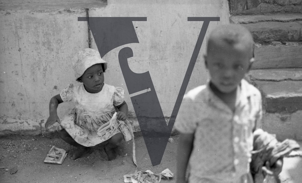 Jamaica, Little girl sits on floor, boy looks at camera.